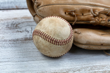 Fototapeta na wymiar Close up of a used baseball and mitt on white vintage wooden background