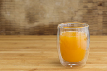 Fresh orange juice on a drinking glass on a wooden surface background
