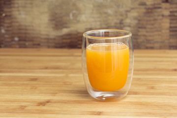 Fresh orange juice on a drinking glass on a wooden surface background