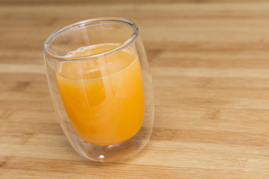 Fresh orange juice on a drinking glass on a wooden surface background