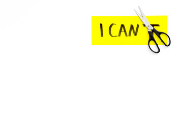 Self confidence concept. Cutting the letter t of written word I can't by sciccors. White background top view copy space