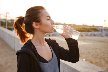 Attractive beautiful young sports woman drinking water