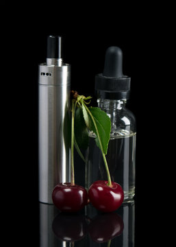 Electronic cigarette and a container with cherry extract stand on a black background