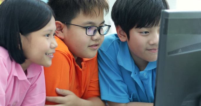 Close up of Smiling asian pupils using a desktop computer in the classroom with smile face.
