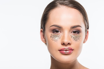 portrait of attractive woman with glitter under eyes looking at camera isolated on white