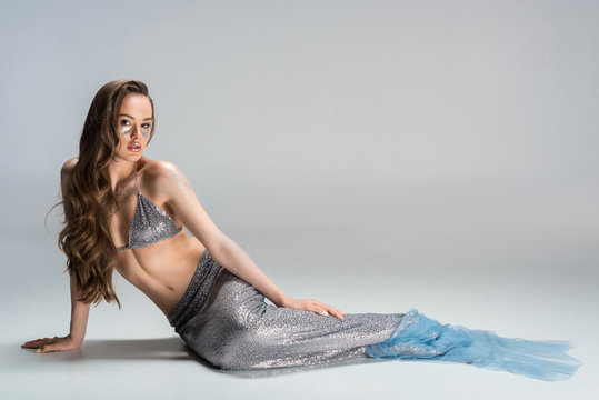 beautiful woman with mermaid tail lying on floor and looking at camera