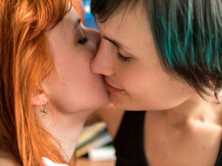 Portrait of two pretty girlfriends kissing