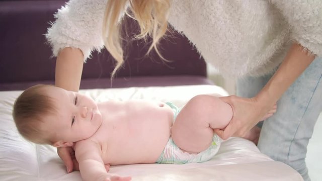 Mom putting child to change diapers. Cute baby lying in diaper on change table. Woman prepare kid to change nappy. Mothercare baby