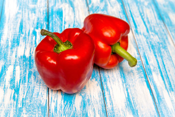 Two red peppers lying on a blue background 