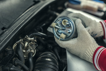 An auto mechanic replaces a car's fuel filter.