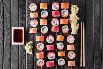 Large set of rolls with garnish and hashi on wooden plate