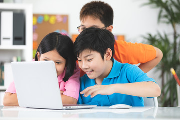 Cute Asian children using laptop together.