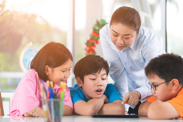 Asian teacher and kids entertaining themselves using digital tablet