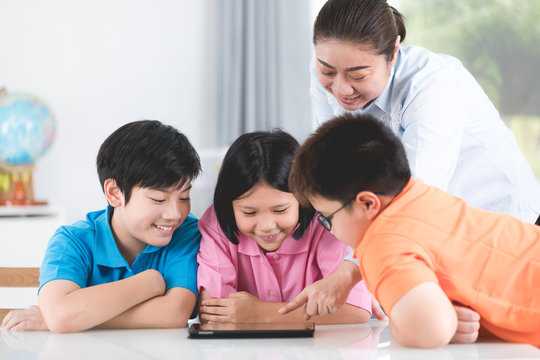 Asian teacher and kids entertaining themselves using digital tablet