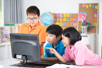 Close up of Smiling asian pupils using a desktop computer.