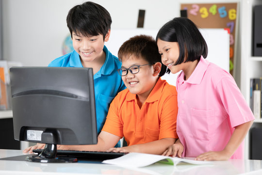 Close up of Smiling asian pupils using a desktop computer.