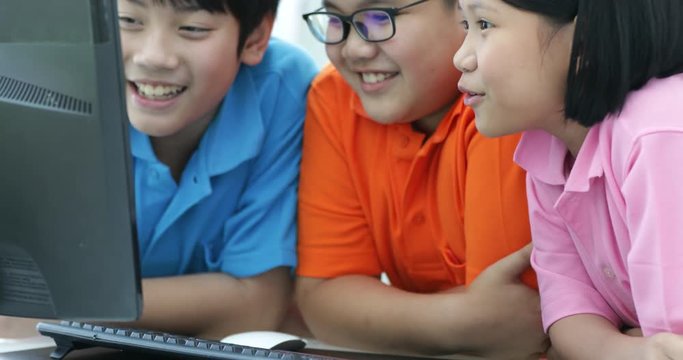Close up of Smiling asian pupils using a desktop computer in the classroom with smile face.