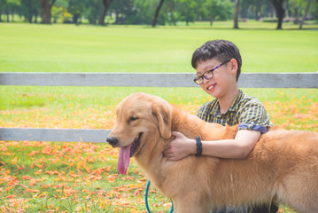 Young asian boy sitting and talking with his dog in park