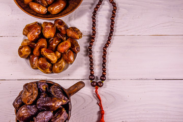 Date fruits and rosary on wooden table. Top view