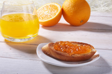 Fototapeta na wymiar Morning Breakfast set with orange jam on bread toast and juice in glass.