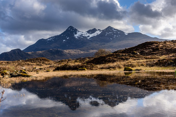 Beautiful reflection of Sgurr nan Gillean in the calm waters of a mountain lake with dramatic...