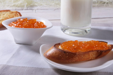Morning Breakfast set with orange jam on bread toast and milk in glass.