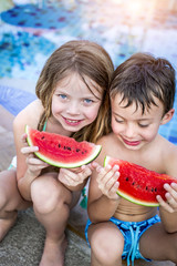 Summer vacation - children eat watermelon by the pool