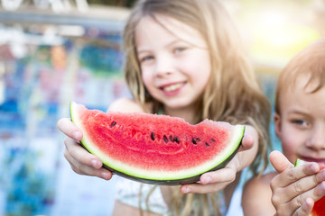 Summer vacation - children eat watermelon by the pool