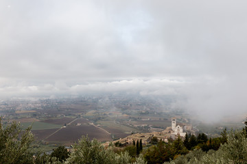 View of St. Francis papal church in Assisi (Umbria, Italy) in the middle of lifting morning fog
