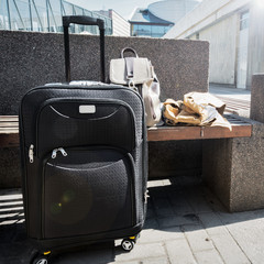 Large black wheeled suitcase standing on the floor in airport, a woman's backpack and cloak on the...