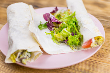 Preparation of a roll of pita bread and fresh vegetables on a wooden background. The concept of healthy eating.