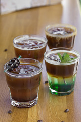 Cold coffees with mint leaves, orange, amarena fruits and ice cubes on the bar