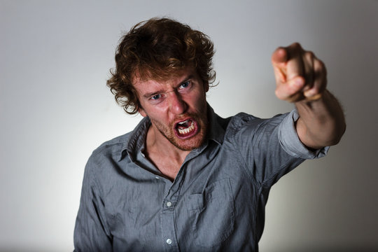 Angry young man shouting and pointing his finger