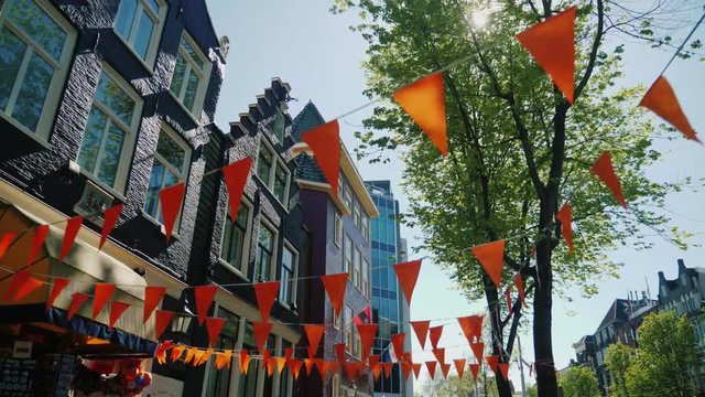 Walking in the streets of Amsterdam. Old houses and triangular orange flags at the top. Steadicam pov video, low angle shot
