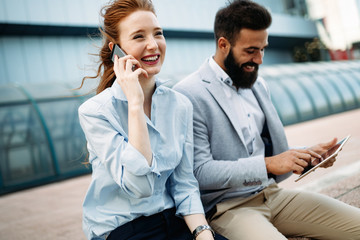 Business man and woman working outdoors with tablet computer in front of office