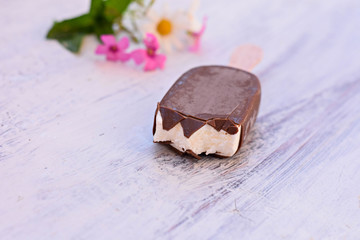 Delicious bitten classic vanilla ice cream covered whit chocolate isolated at light wooden background