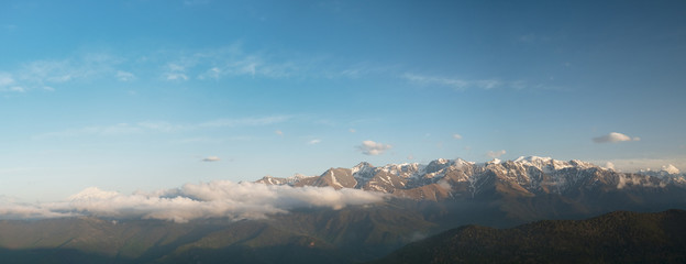 the tops of the mountain ranges snow-covered in the clouds of the Karachay-Cherkess Republic, the Caucasus, in the spring evening