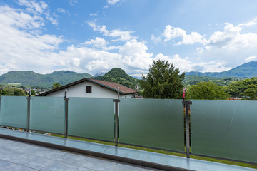 A glass parapet of a modern building balcony overlooking hills