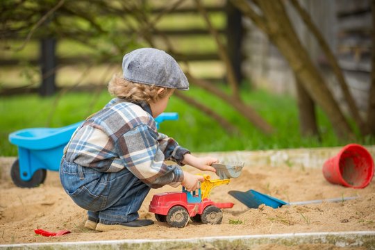 Small caucasian boy playing in sandpit