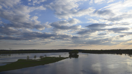 Photo of the spilling on the river in spring, green meadow and bright sky with small clouds