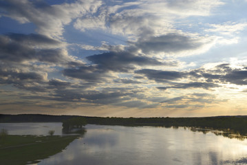 Photo of the spilling on the river in spring, green meadow and bright sky with small clouds