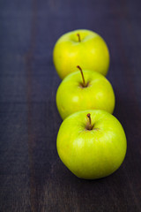 Three apples on a dark wooden background