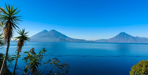 Tuinposter View from Lake Atitlan in the early morning, blue skys and clear water, beautiful magic lake with volcanos and indigenous people in the highland of Guatemala  © Simon Dannhauer
