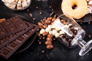 Candies and donuts next to other sweets on dark vintage wooden background