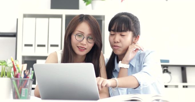 Asian senior worker are teaching new worker .They are work with laptop computer with smile face.