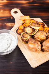 Dinner made of fried chicken and grilled vegetables and a glass bowl of sour cream souce