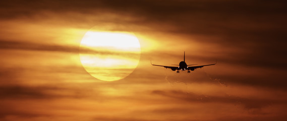Beautiful sunset with airplane landing