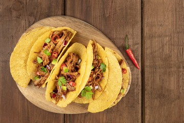 Overhead photo of Mexican tacos with pulled meat, avocado, chili peppers, cilantro, with place for text