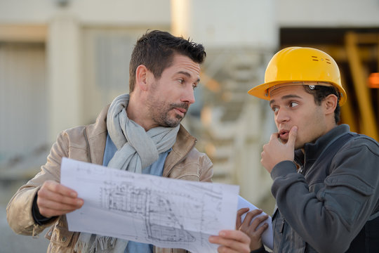 male architect with worker discussing at construction site