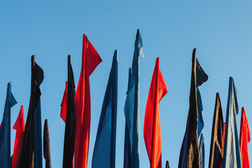 Red, blue, black flags against the blue sky